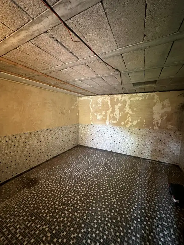 Vorher: leerer Kellerraum mit Mosaikfliesen, abgeplatztem Putz und offener Decke